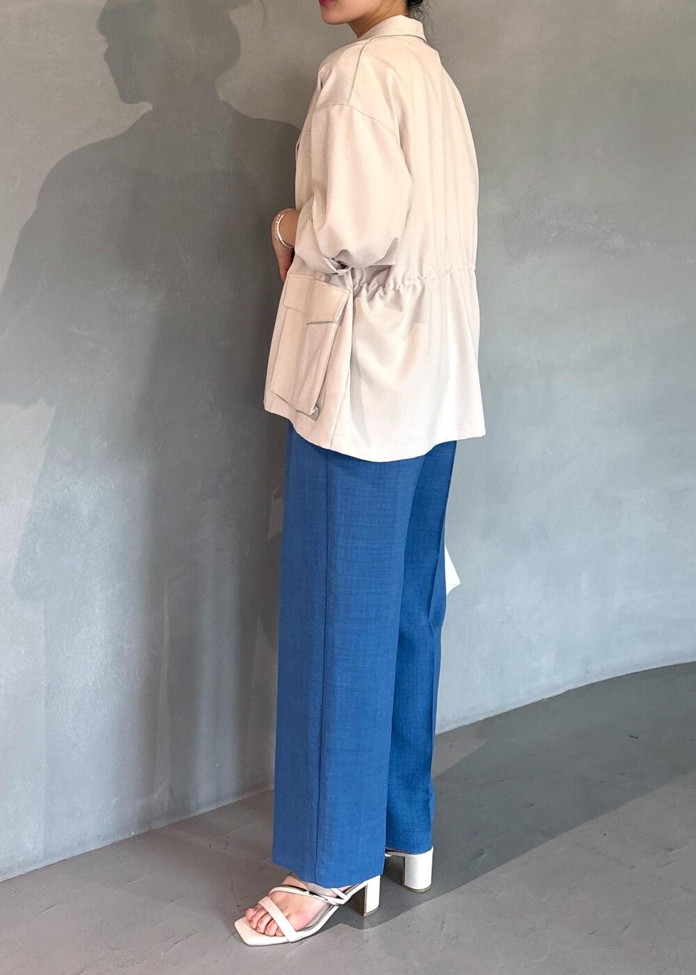 ホワイト系のミリタリージャケット、ブルー系のスラックス、ホワイト系のニット/セーターを着用したレディースの春コーディネートの7枚目の写真