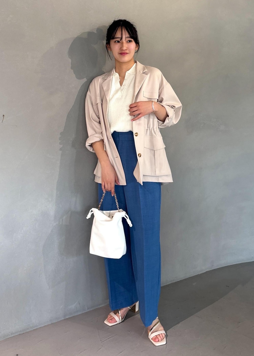 ホワイト系のミリタリージャケット、ブルー系のスラックス、ホワイト系のニット/セーターを着用したレディースの春コーディネートの5枚目の写真