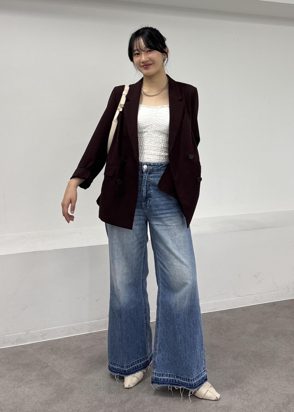 ホワイト系のショルダーバッグ、ブルー系のデニムパンツ、ホワイト系のパンプスを着用したレディースの夏コーディネートの2枚目の写真