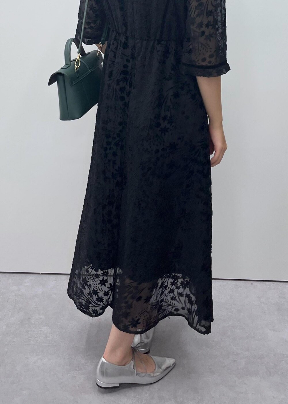 シルバー系のパンプス、グリーン系のショルダーバッグ、ブラック系のドレスを着用したレディースの秋コーディネートの5枚目の写真