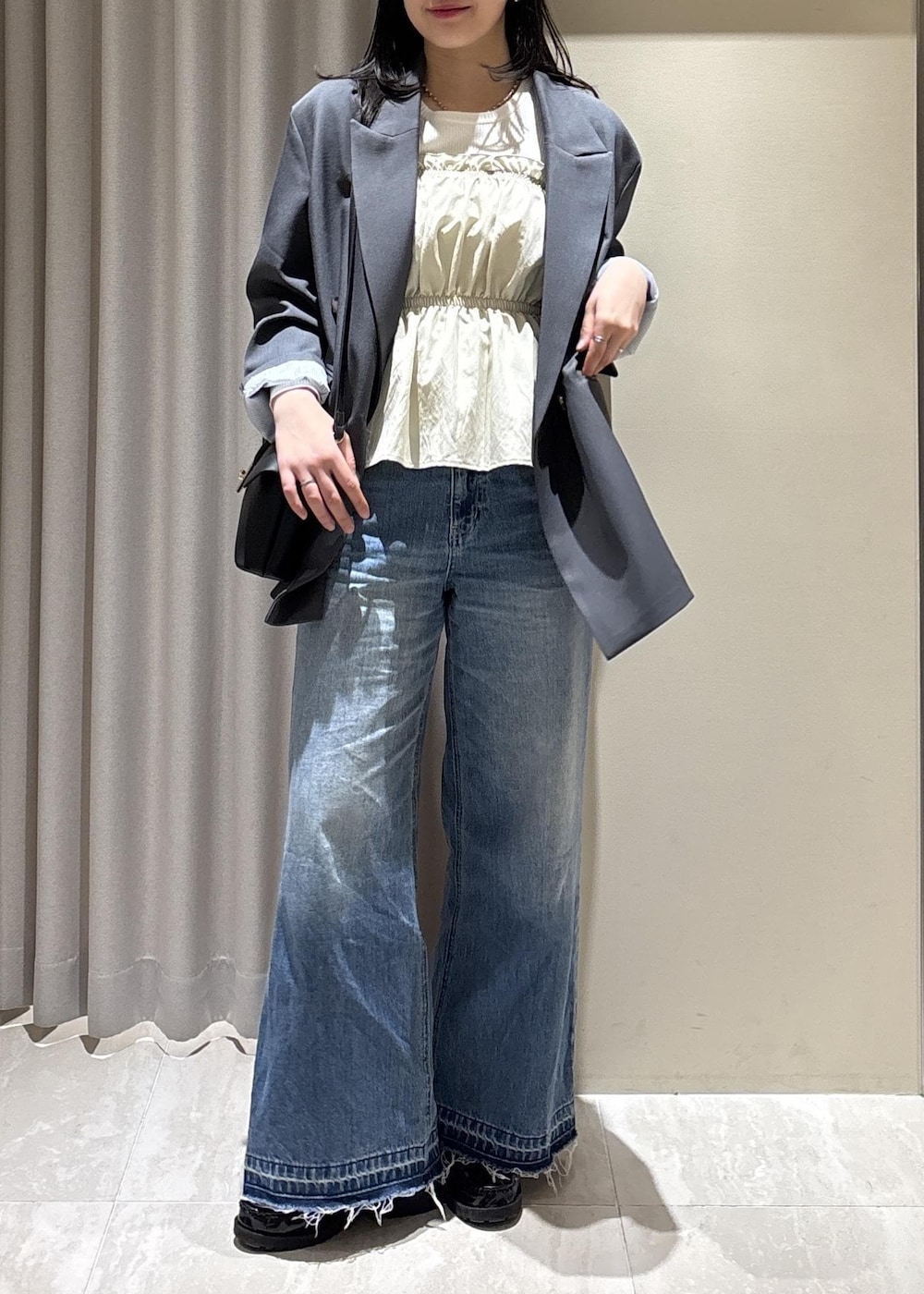 ブラック系のショルダーバッグ、ブルー系のデニムパンツ、ホワイト系のニット/セーターを着用したレディースの春コーディネートの7枚目の写真