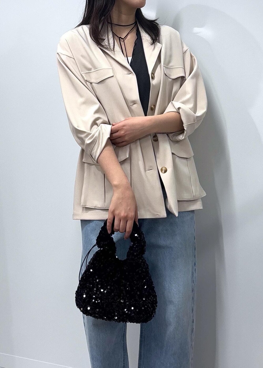 ブルー系のデニムパンツ、ブラック系のパンプス、ホワイト系のミリタリージャケットを着用したレディースの春コーディネートの3枚目の写真