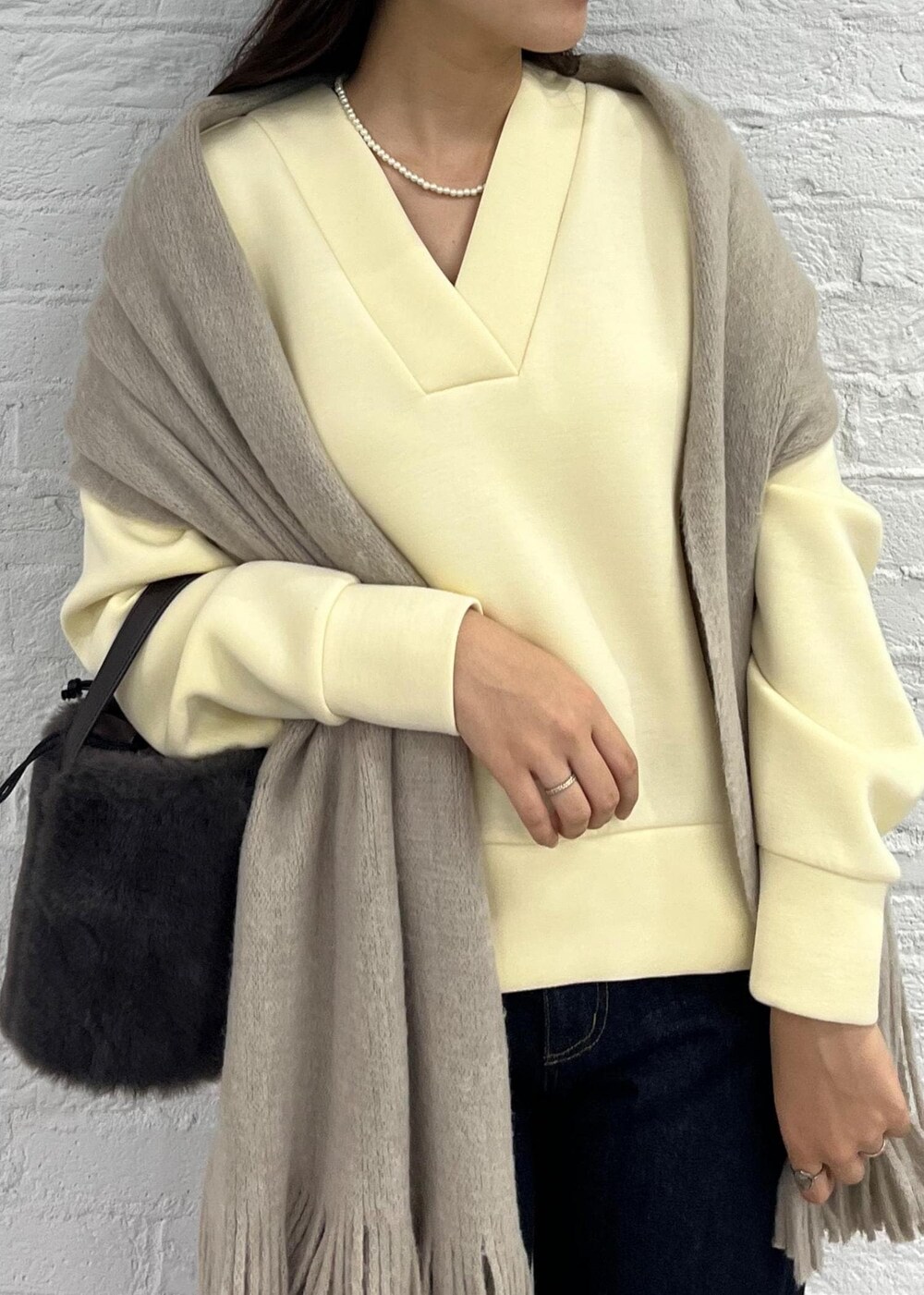 ブルー系のデニムパンツ、グレー系のショルダーバッグ、ベージュ系のその他トップスを着用したレディースの秋コーディネートの5枚目の写真