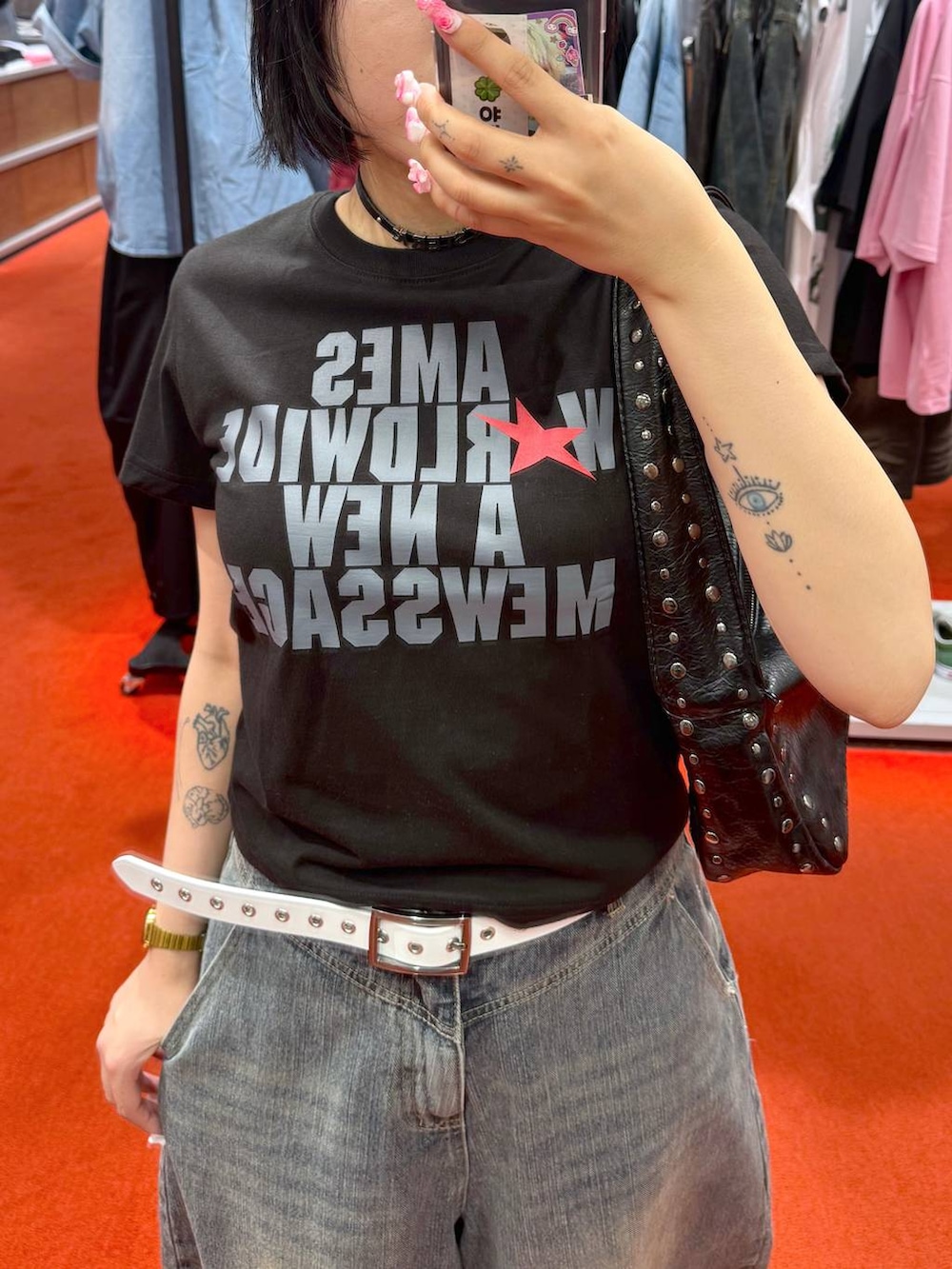 ブルー系のデニムパンツ、ブラック系のTシャツ/カットソー、ブラック系のハンドバッグを着用したレディースの夏コーディネートの2枚目の写真