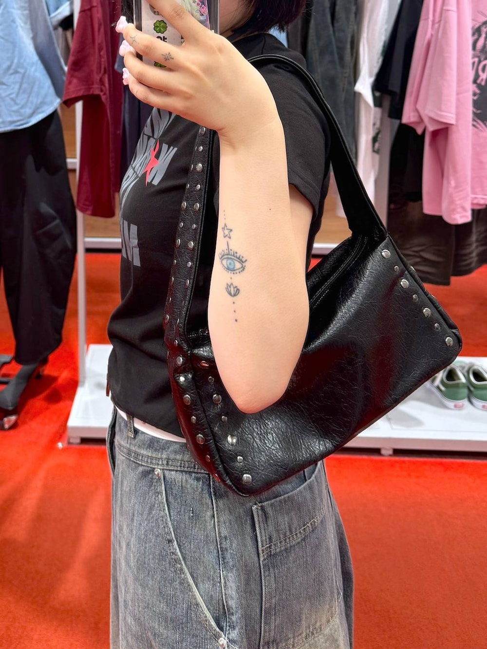 ブルー系のデニムパンツ、ブラック系のTシャツ/カットソー、ブラック系のハンドバッグを着用したレディースの夏コーディネートの3枚目の写真