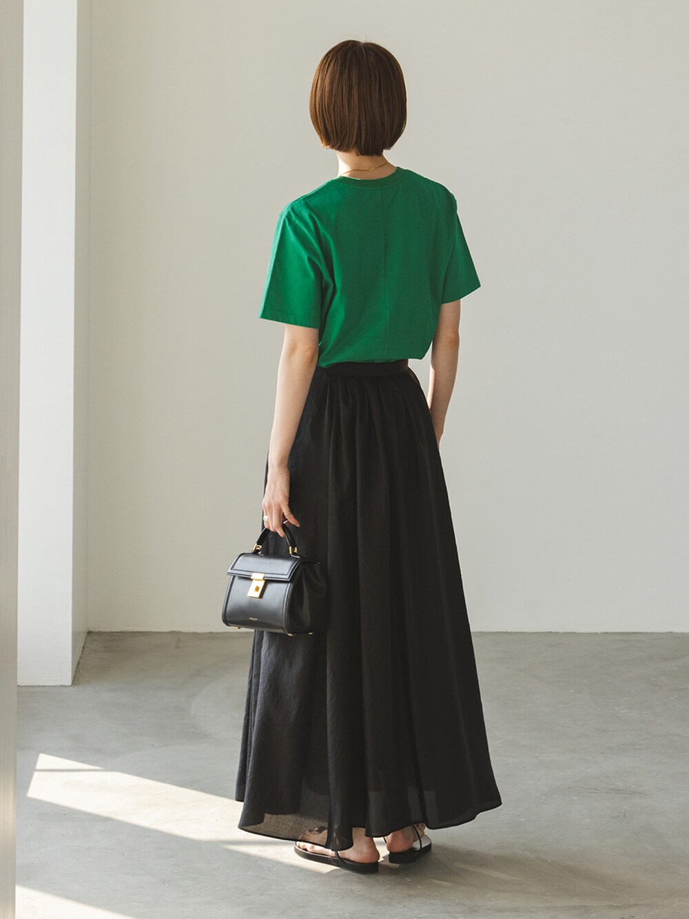 グリーン系のTシャツ/カットソー、ブラック系のスカートを着用したレディースの夏コーディネートの2枚目の写真