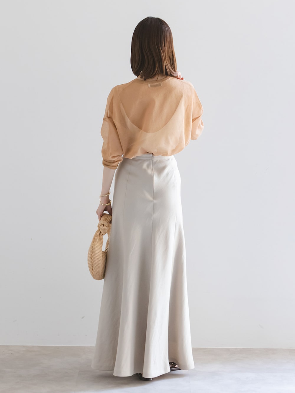 イエロー系のニット/セーター、ホワイト系のキャミソール、ベージュ系のスカートを着用したレディースの春コーディネートの3枚目の写真