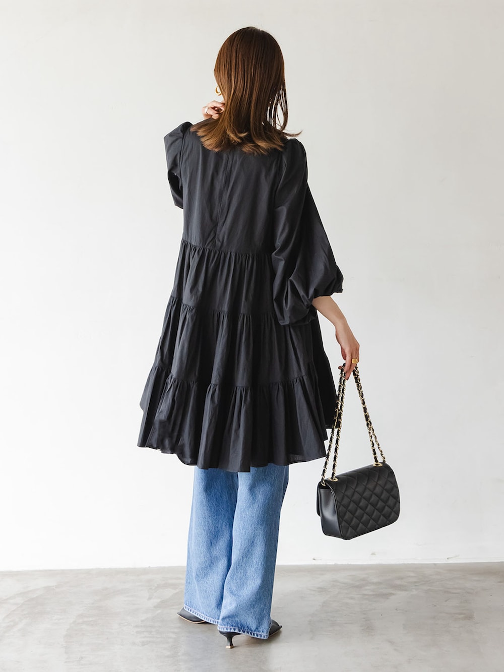 ブラック系のワンピース、ブルー系のデニムパンツ、ブラック系のショルダーバッグを着用したレディースの夏コーディネートの3枚目の写真