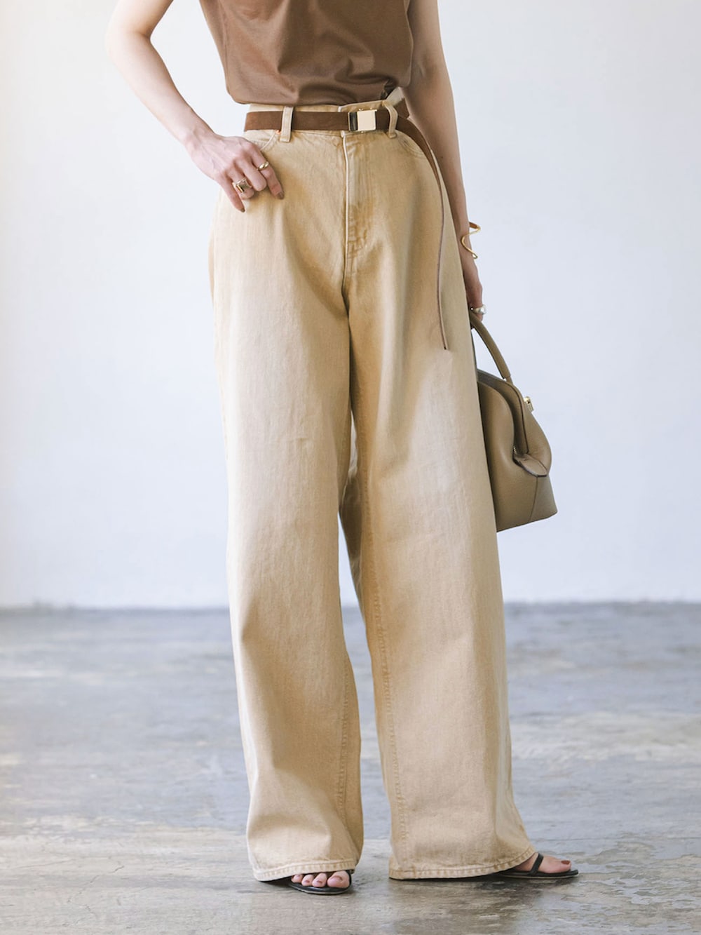 ベージュ系のデニムパンツ、ブラウン系のTシャツ/カットソー、ベージュ系のショルダーバッグを着用したレディースの夏コーディネートの3枚目の写真