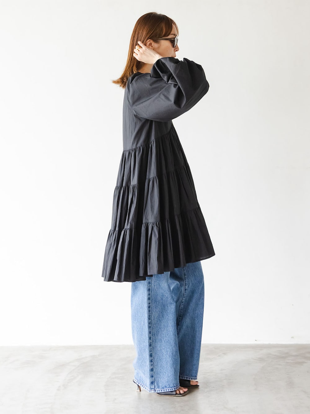 ブラック系のワンピース、ブルー系のデニムパンツ、ブラック系のショルダーバッグを着用したレディースの夏コーディネートの2枚目の写真
