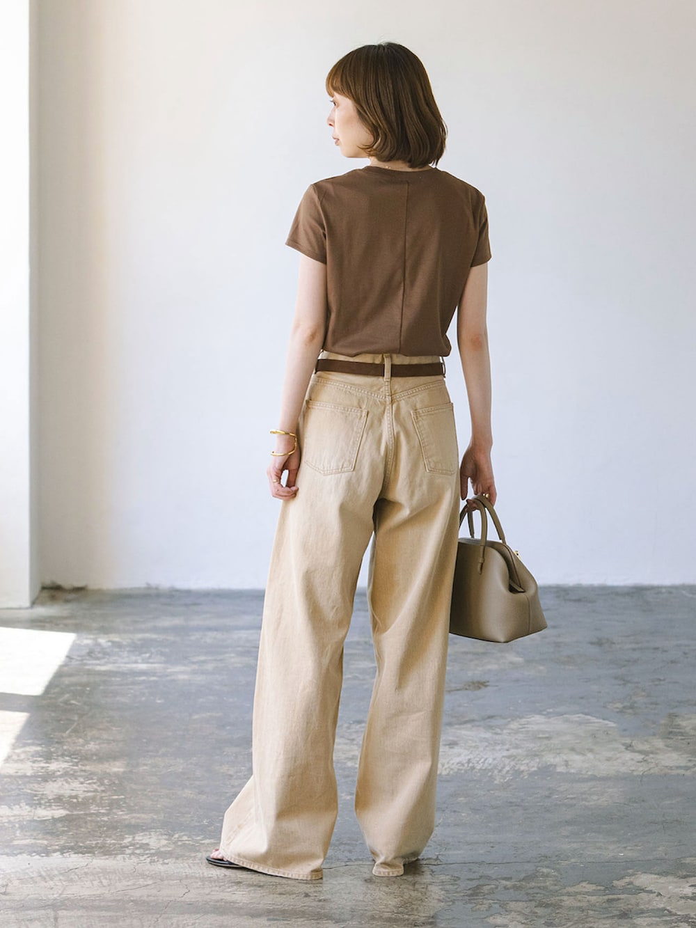 ベージュ系のデニムパンツ、ブラウン系のTシャツ/カットソー、ベージュ系のショルダーバッグを着用したレディースの夏コーディネートの2枚目の写真