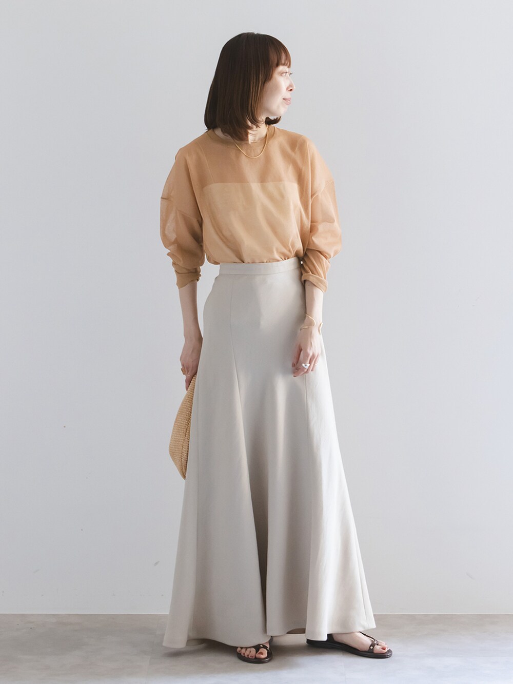 イエロー系のニット/セーター、ホワイト系のキャミソール、ベージュ系のスカートを着用したレディースの春コーディネートの2枚目の写真