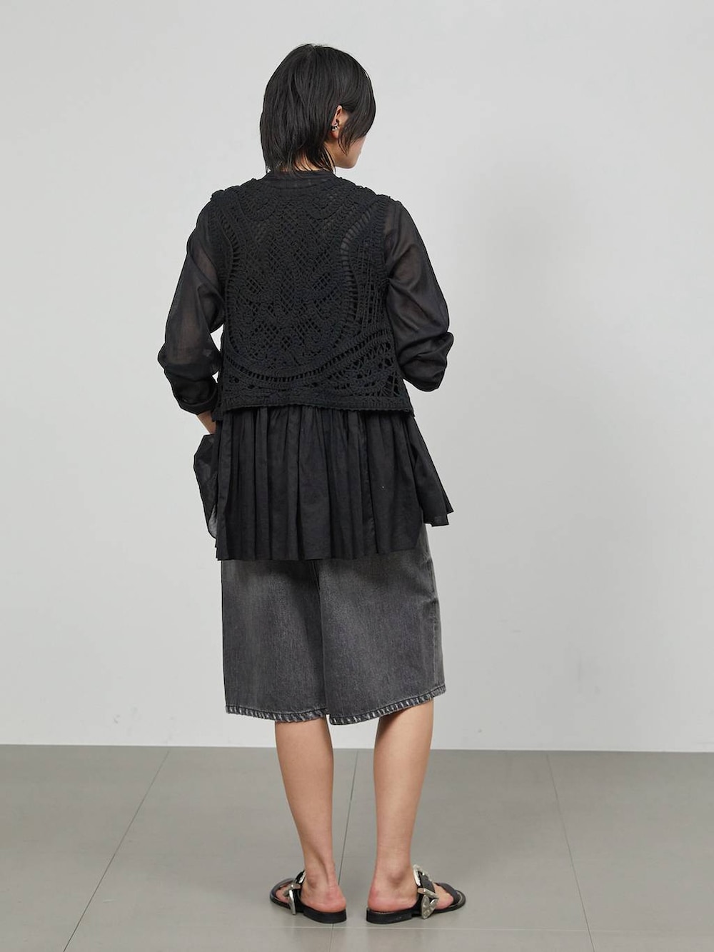 ブラック系のデニムパンツ、ブラック系のベストを着用したレディースの冬コーディネートの4枚目の写真