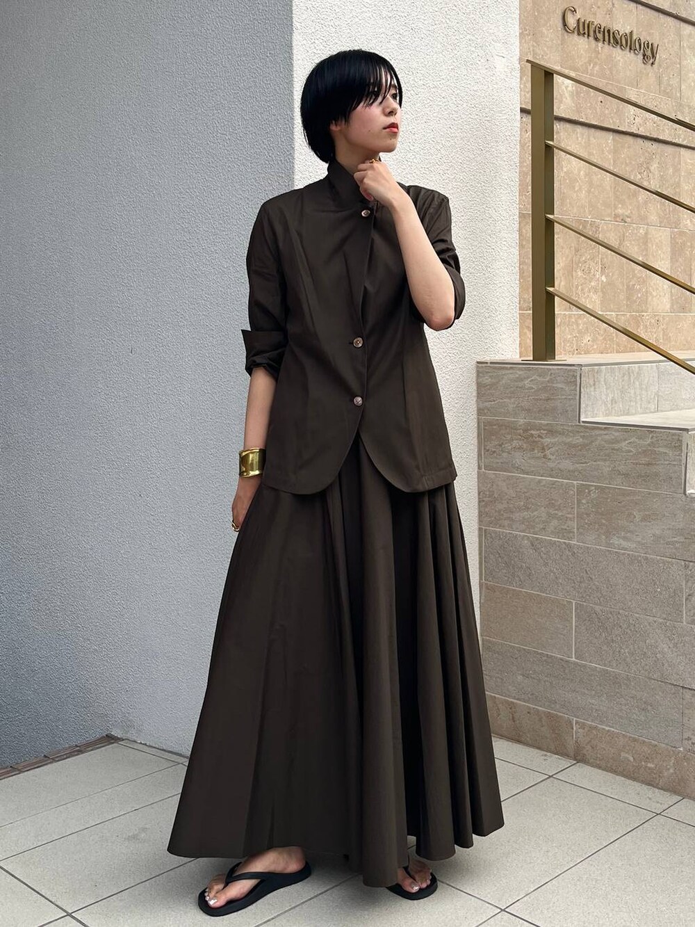 ブラック系のサンダル、グリーン系のスカート、グリーン系のテーラードジャケットを着用したレディースの夏コーディネートの2枚目の写真