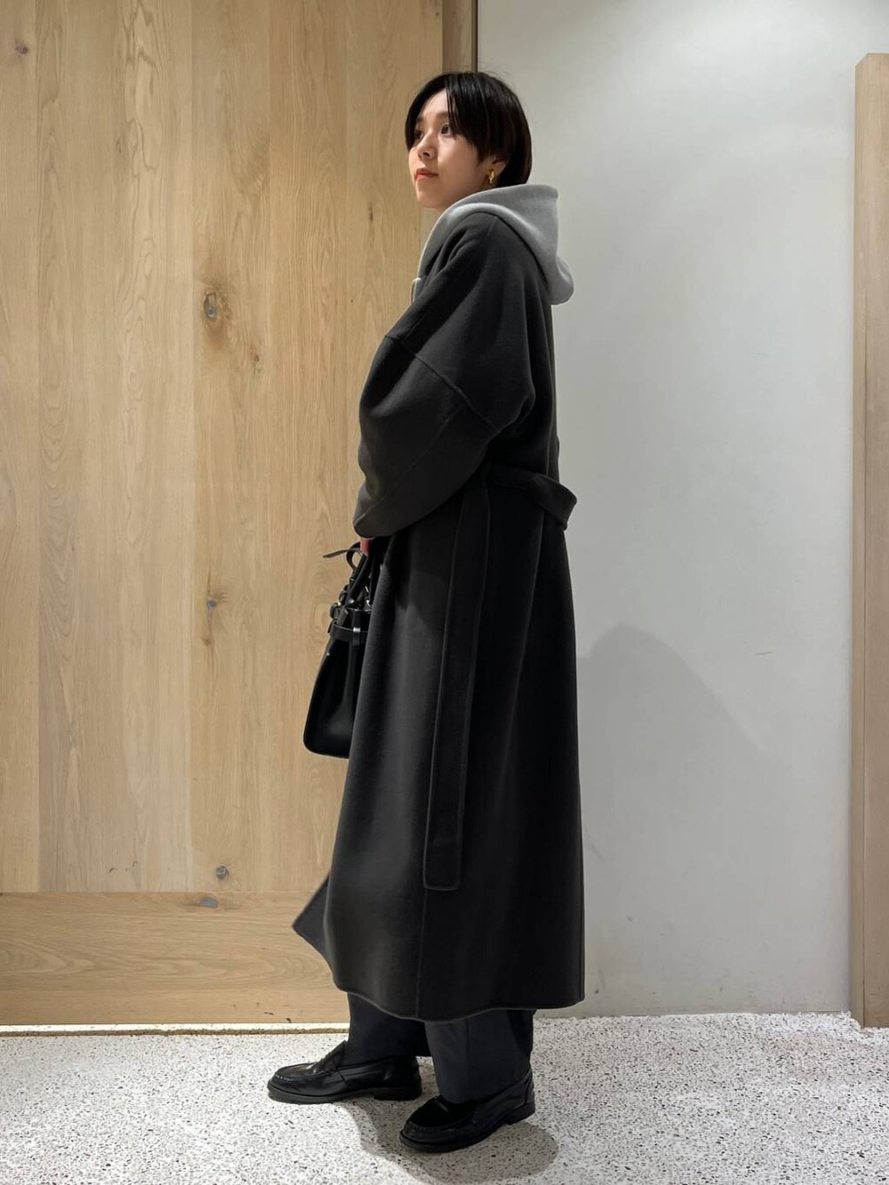 グレー系のノーカラーコート、グレー系のその他パンツ、グレー系のパーカーを着用したレディースの秋コーディネートの2枚目の写真