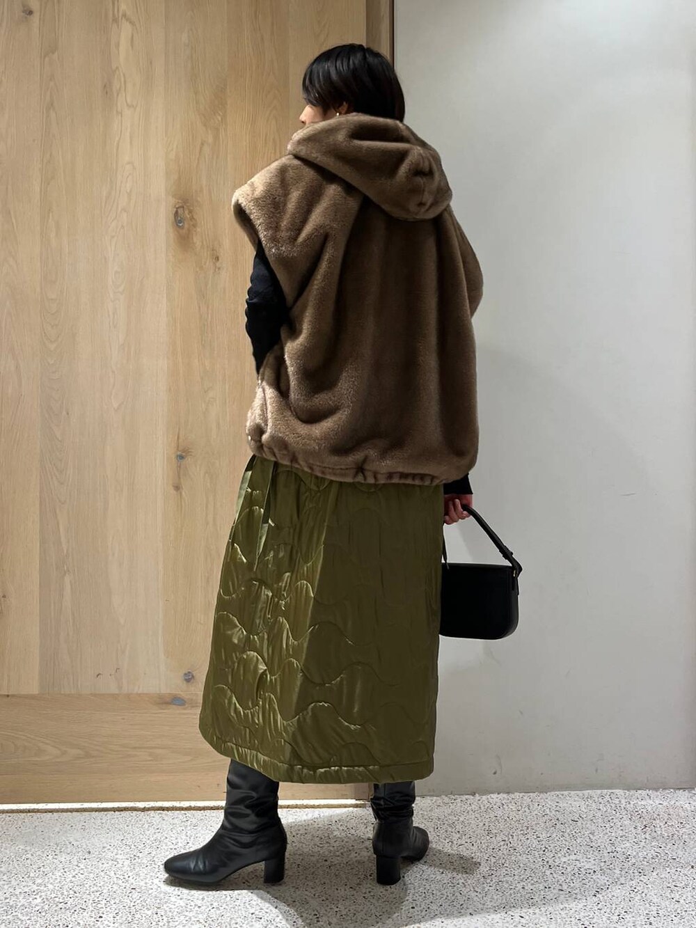 ブラック系のニット/セーター、ブラウン系のベスト、ブラック系のワンピースを着用したレディースの冬コーディネートの2枚目の写真