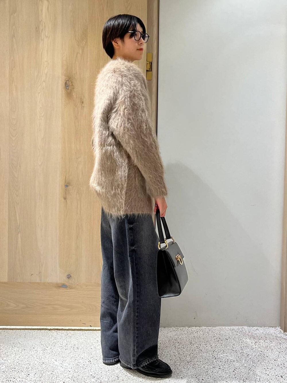 ブラック系のデニムパンツ、ベージュ系のカーディガン/ボレロ、ブラック系のTシャツ/カットソーを着用したレディースの秋コーディネートの2枚目の写真