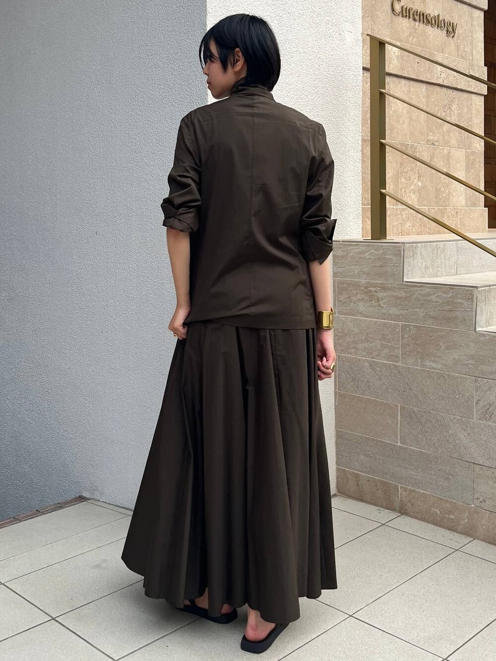 ブラック系のサンダル、グリーン系のスカート、グリーン系のテーラードジャケットを着用したレディースの夏コーディネートの3枚目の写真