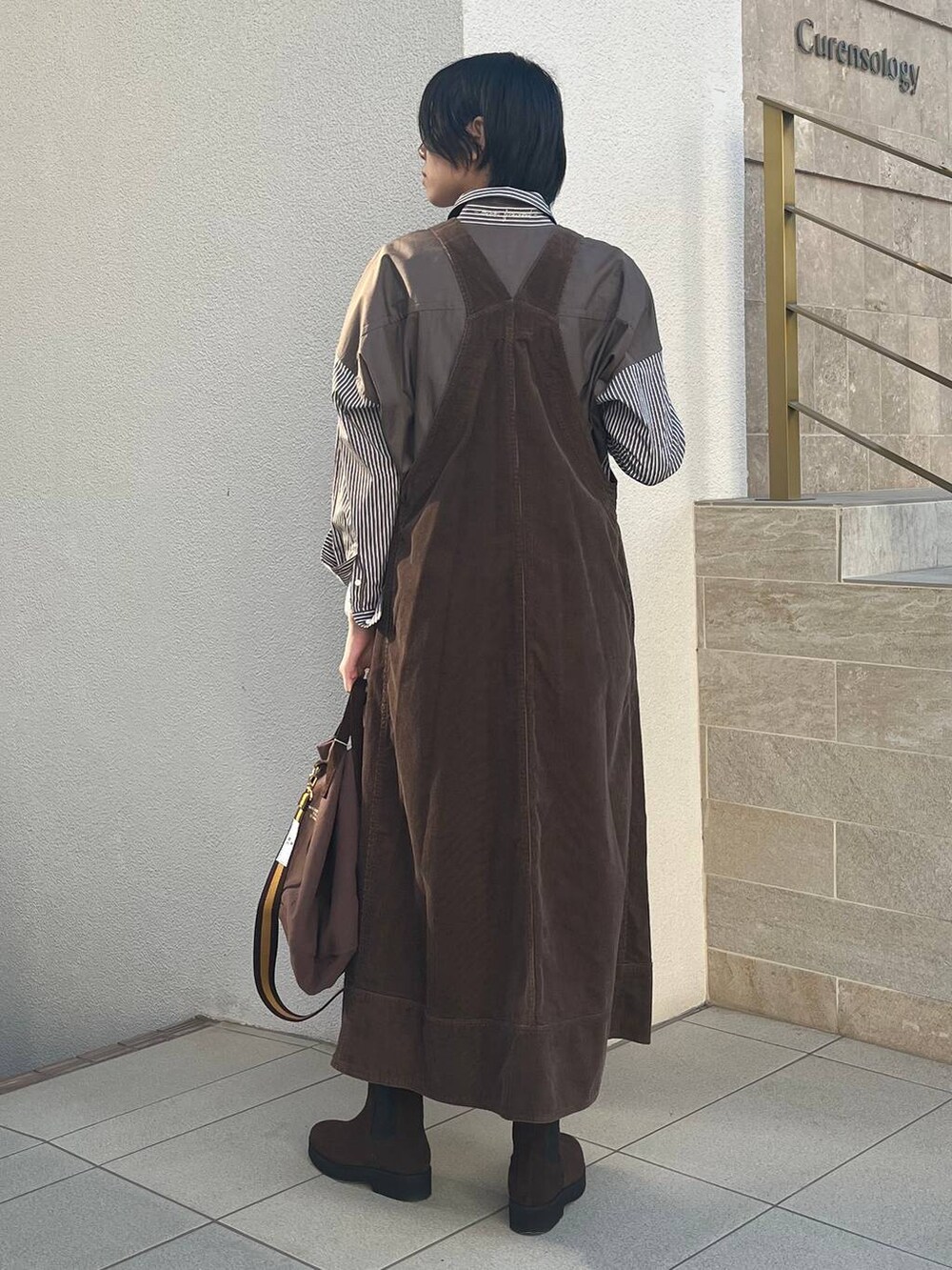 ブラウン系のジャンパースカート、ブラウン系のトートバッグ、ブラウン系のシャツ/ブラウスを着用したレディースの冬コーディネートの3枚目の写真