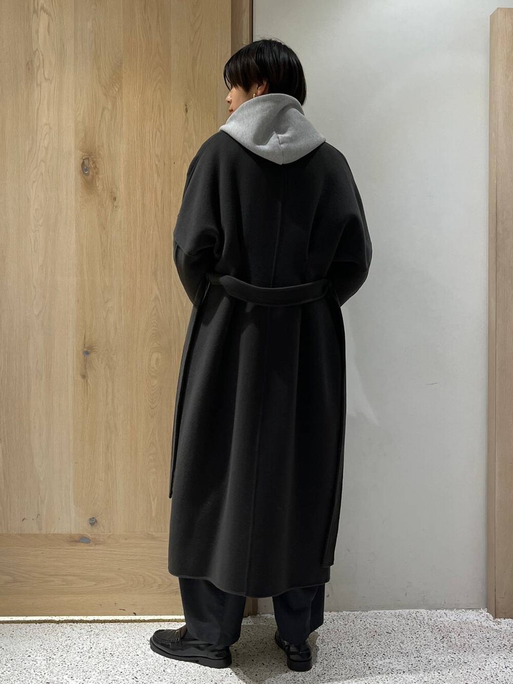 グレー系のノーカラーコート、グレー系のその他パンツ、グレー系のパーカーを着用したレディースの秋コーディネートの3枚目の写真