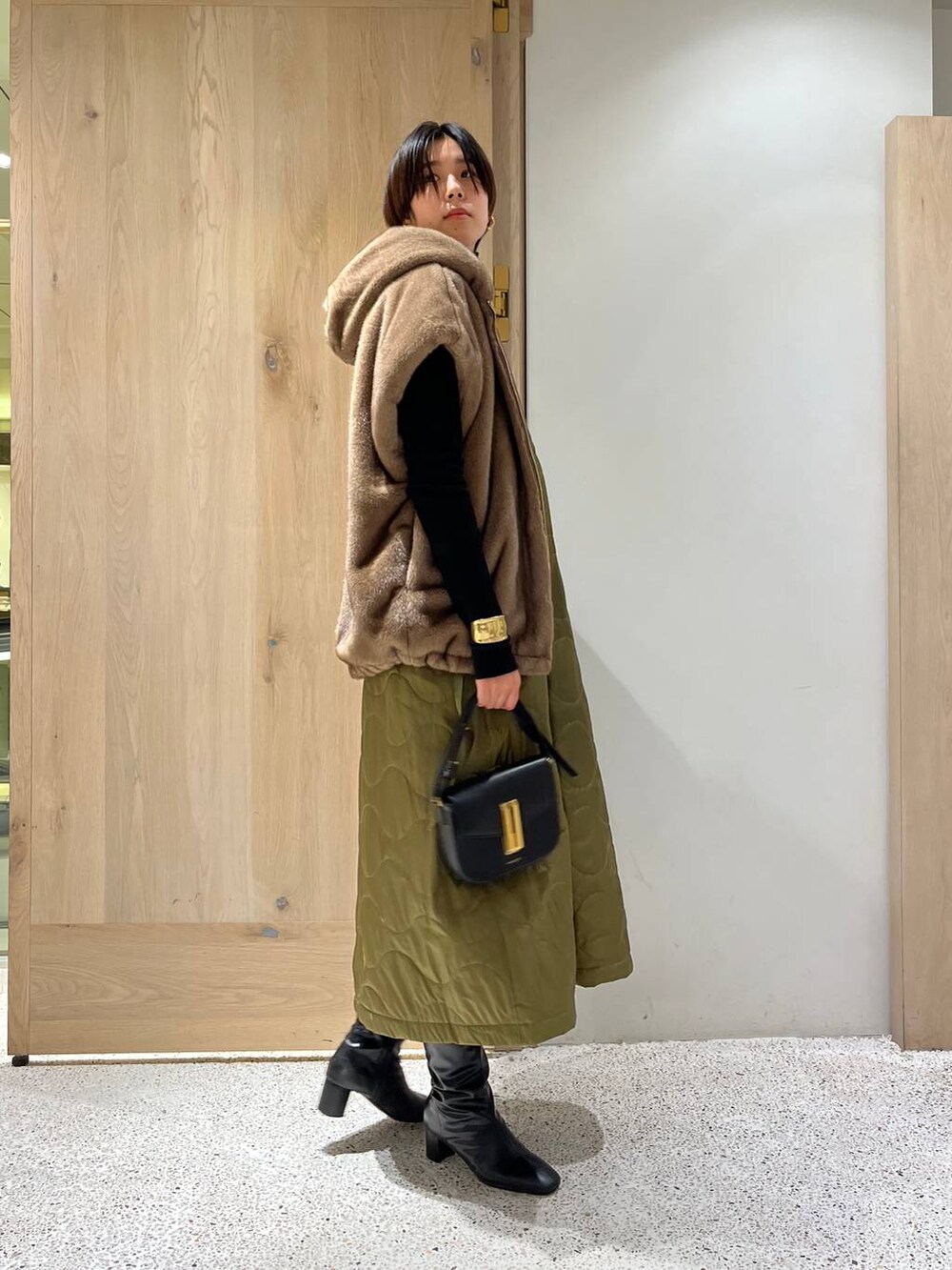 ブラック系のニット/セーター、ブラウン系のベスト、ブラック系のワンピースを着用したレディースの冬コーディネートの3枚目の写真