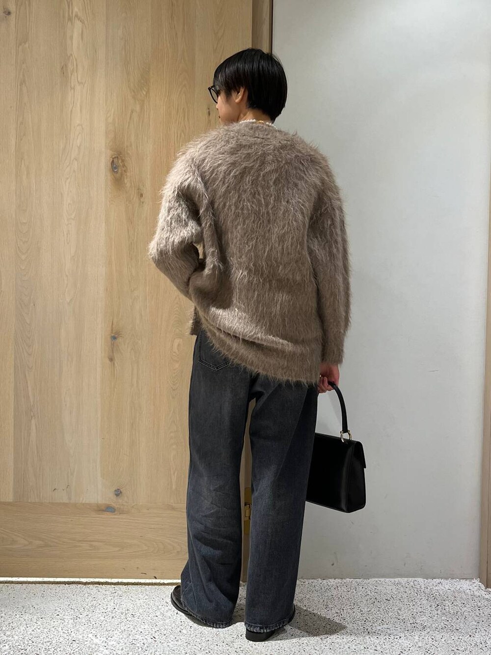 ブラック系のデニムパンツ、ベージュ系のカーディガン/ボレロ、ブラック系のTシャツ/カットソーを着用したレディースの秋コーディネートの3枚目の写真