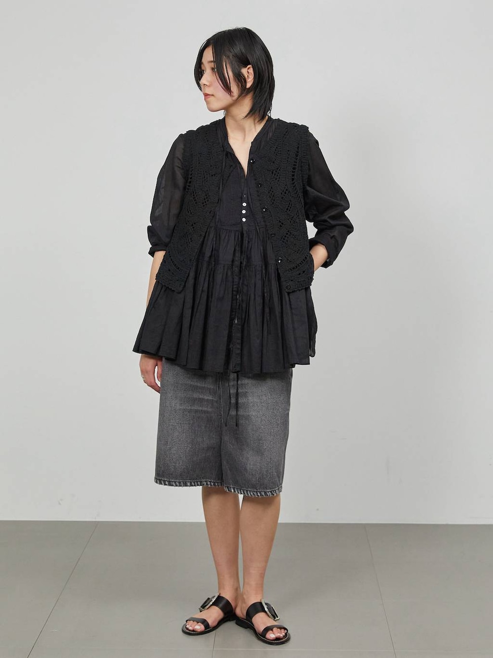 ブラック系のデニムパンツ、ブラック系のベストを着用したレディースの冬コーディネートの2枚目の写真