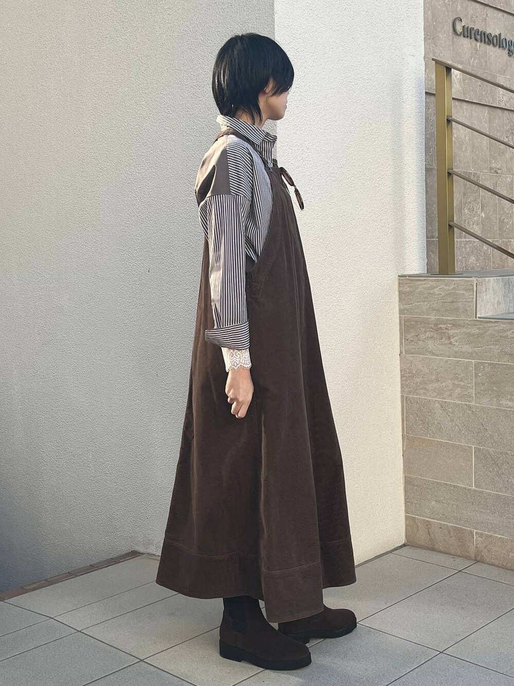 ブラウン系のジャンパースカート、ブラウン系のトートバッグ、ブラウン系のシャツ/ブラウスを着用したレディースの冬コーディネートの2枚目の写真