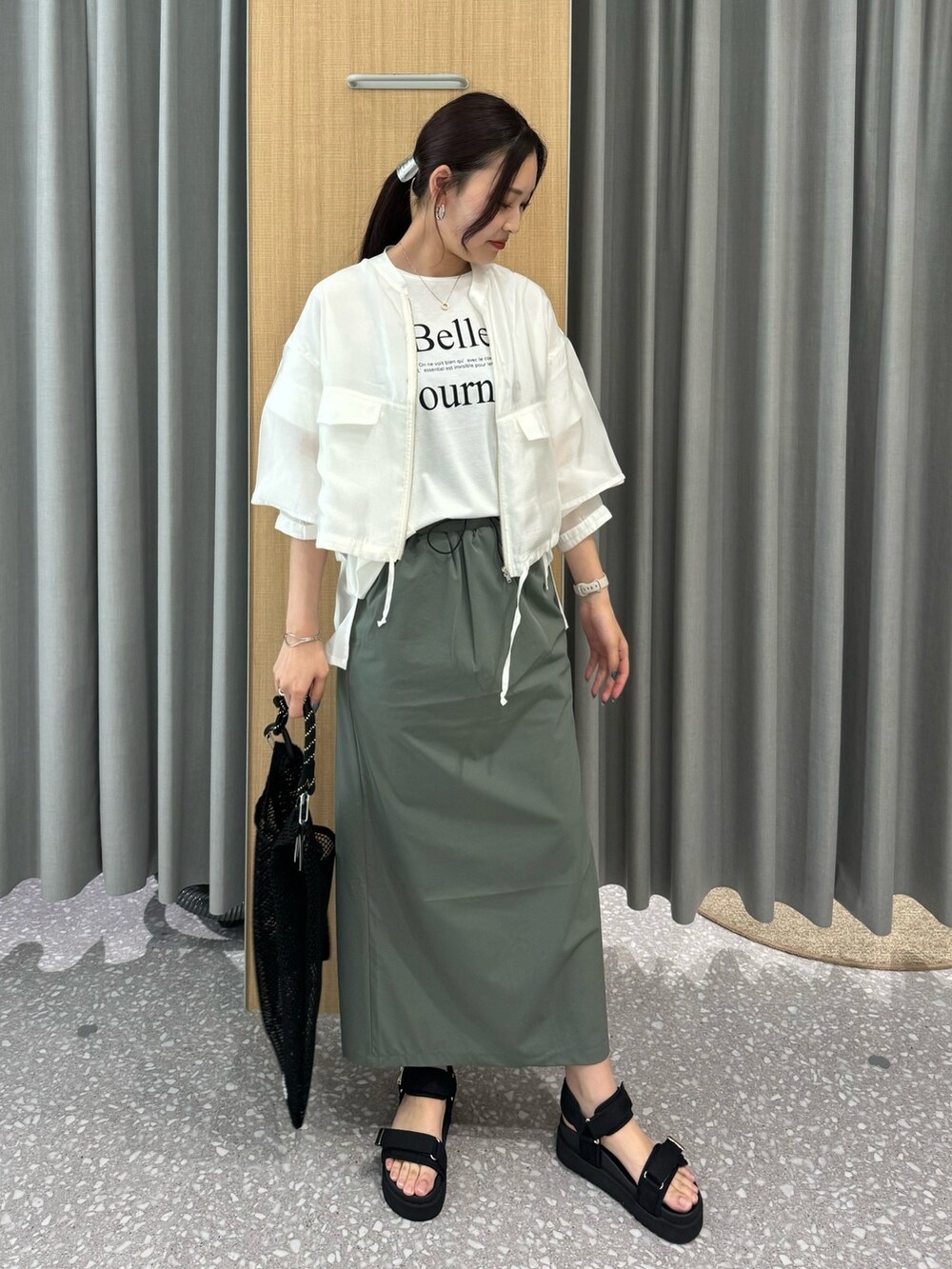 グリーン系のスカート、ホワイト系のブルゾン、ホワイト系のTシャツ/カットソーを着用したレディースの夏コーディネートの2枚目の写真