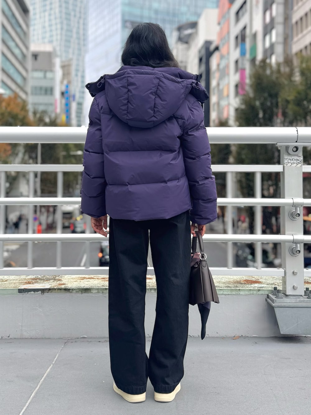 ブラック系のデニムパンツ、ブラウン系のショルダーバッグ、パープル系のスニーカーを着用したレディースの秋コーディネートの3枚目の写真