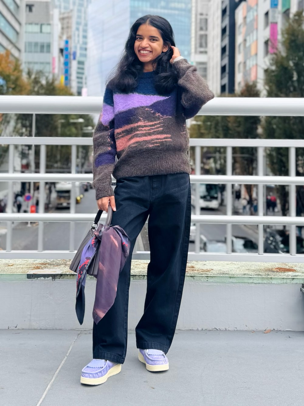 ブラック系のデニムパンツ、ブラウン系のショルダーバッグ、パープル系のスニーカーを着用したレディースの秋コーディネートの2枚目の写真