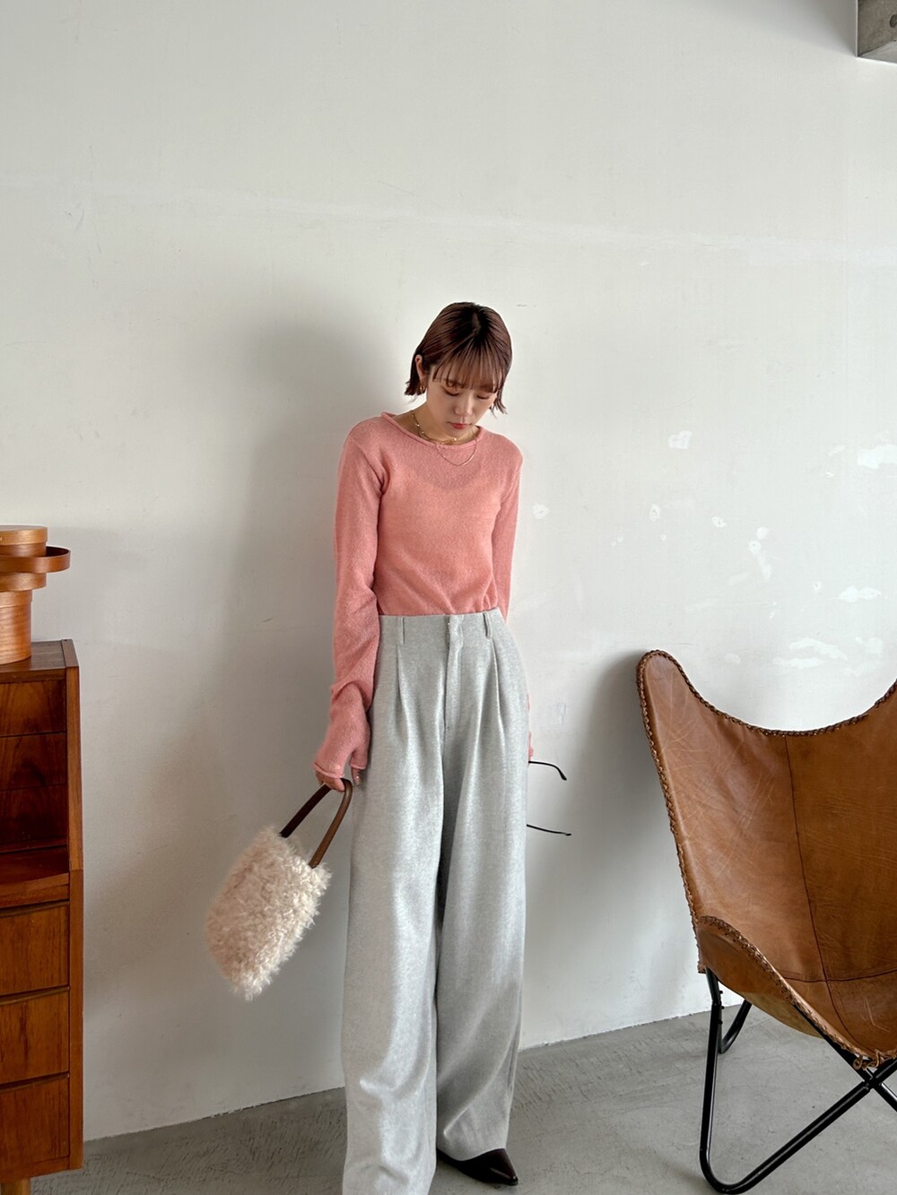 ピンク系のニット/セーター、グレー系のその他パンツ、ホワイト系のハンドバッグを着用したレディースの秋コーディネートの2枚目の写真