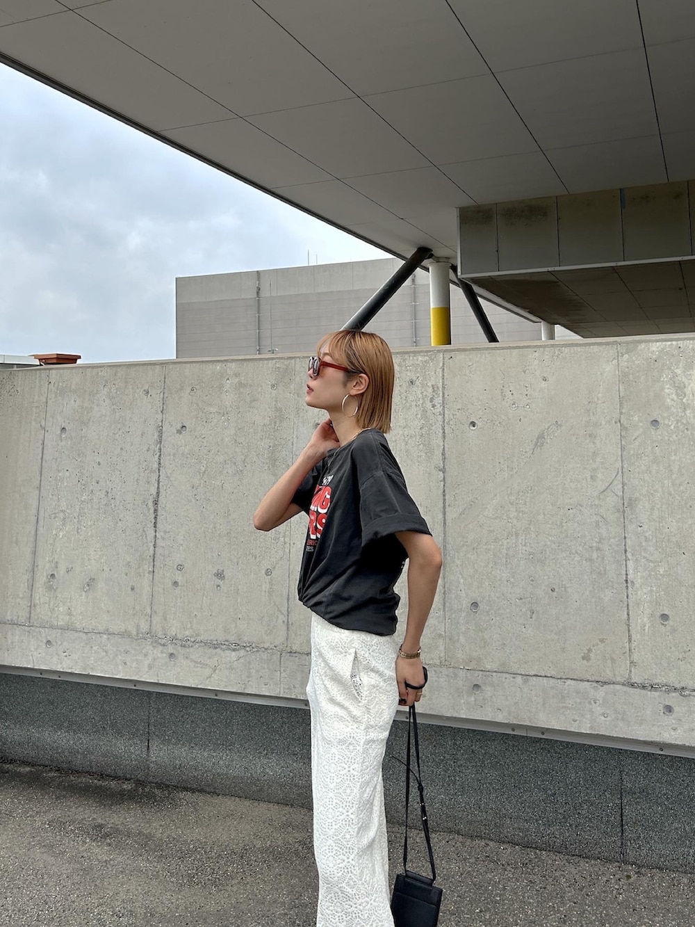 オレンジ系のTシャツ/カットソー、ブラック系のボディバッグ/ウエストポーチ、ブラック系のサンダルを着用したレディースの春コーディネートの4枚目の写真