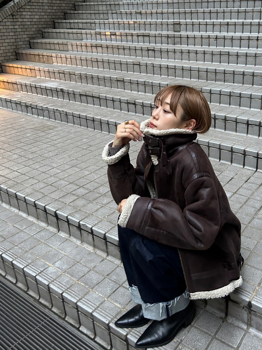 ブラウン系のムートンコート、ブルー系のデニムパンツを着用したレディースの秋コーディネートの3枚目の写真