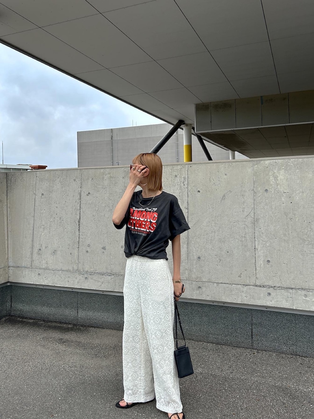 オレンジ系のTシャツ/カットソー、ブラック系のボディバッグ/ウエストポーチ、ブラック系のサンダルを着用したレディースの春コーディネートの2枚目の写真