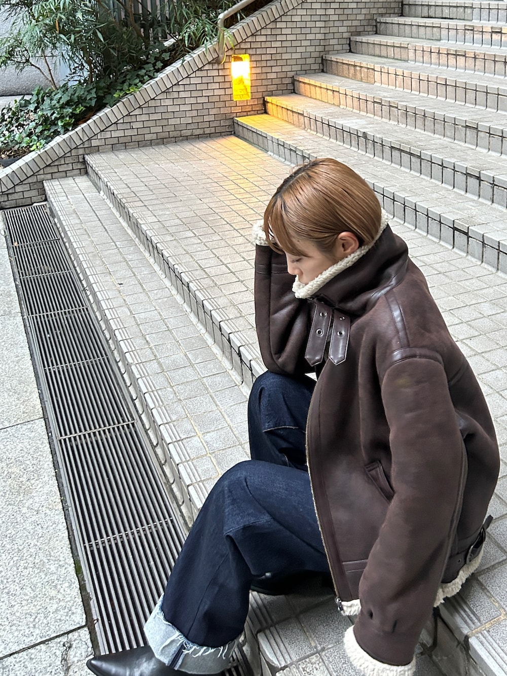 ブラウン系のムートンコート、ブルー系のデニムパンツを着用したレディースの秋コーディネートの2枚目の写真