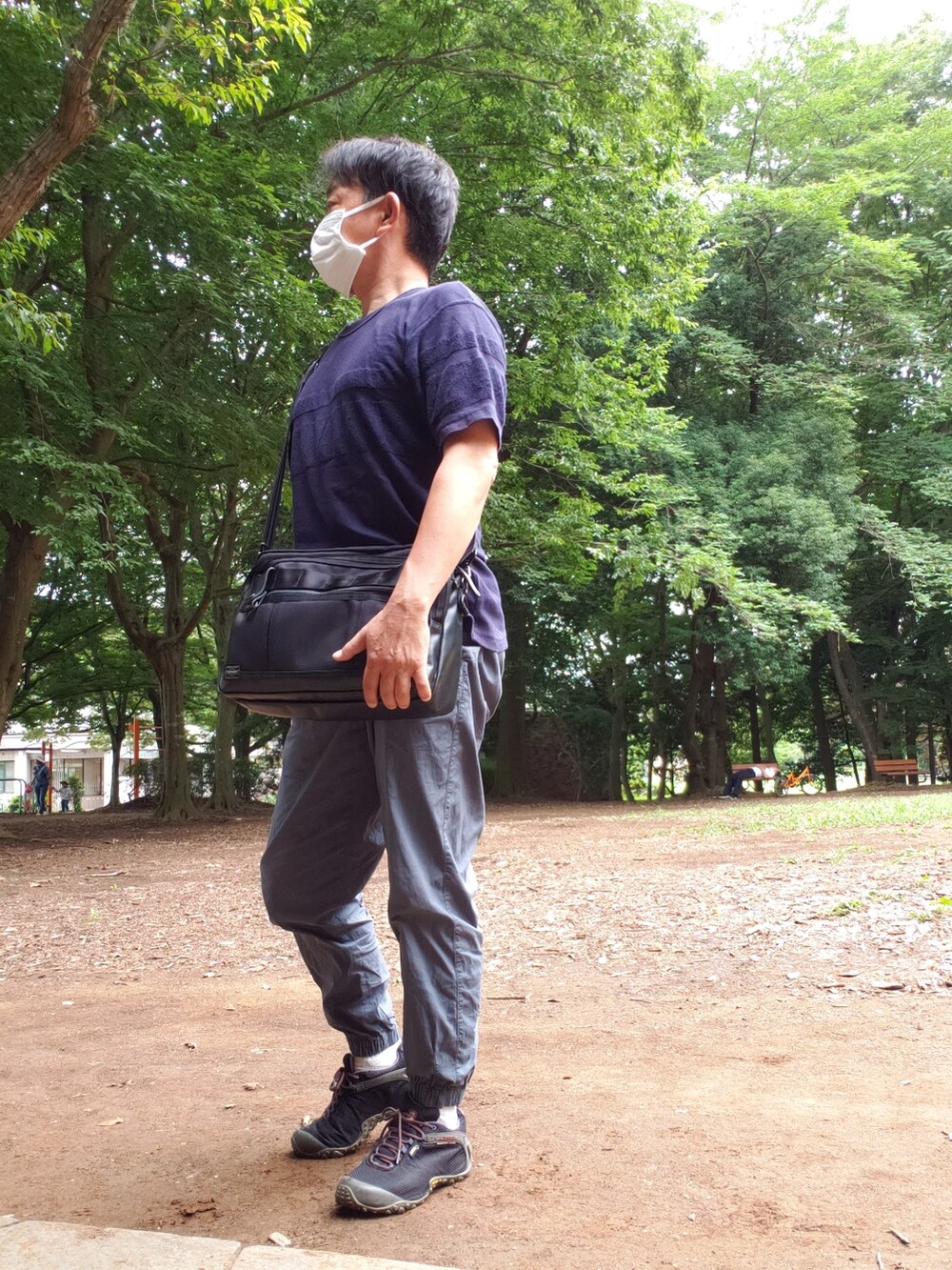 ブラック系のTシャツ/カットソー、ブラック系のショルダーバッグ、ブルー系のカーゴパンツを着用したメンズの夏コーディネートの2枚目の写真