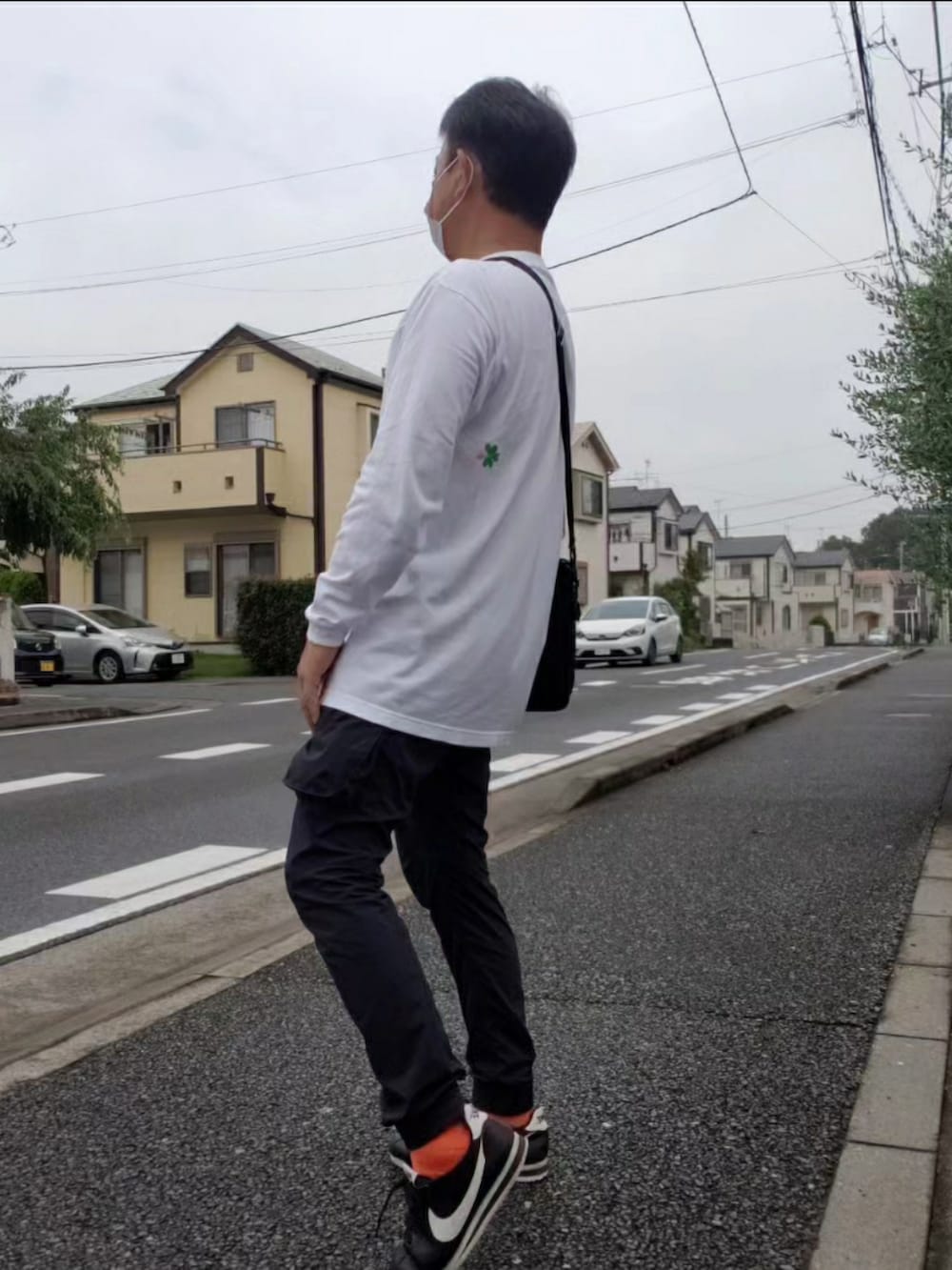 ブラック系のスニーカー、グリーン系のベスト、ホワイト系のTシャツ/カットソーを着用したメンズの秋コーディネートの2枚目の写真