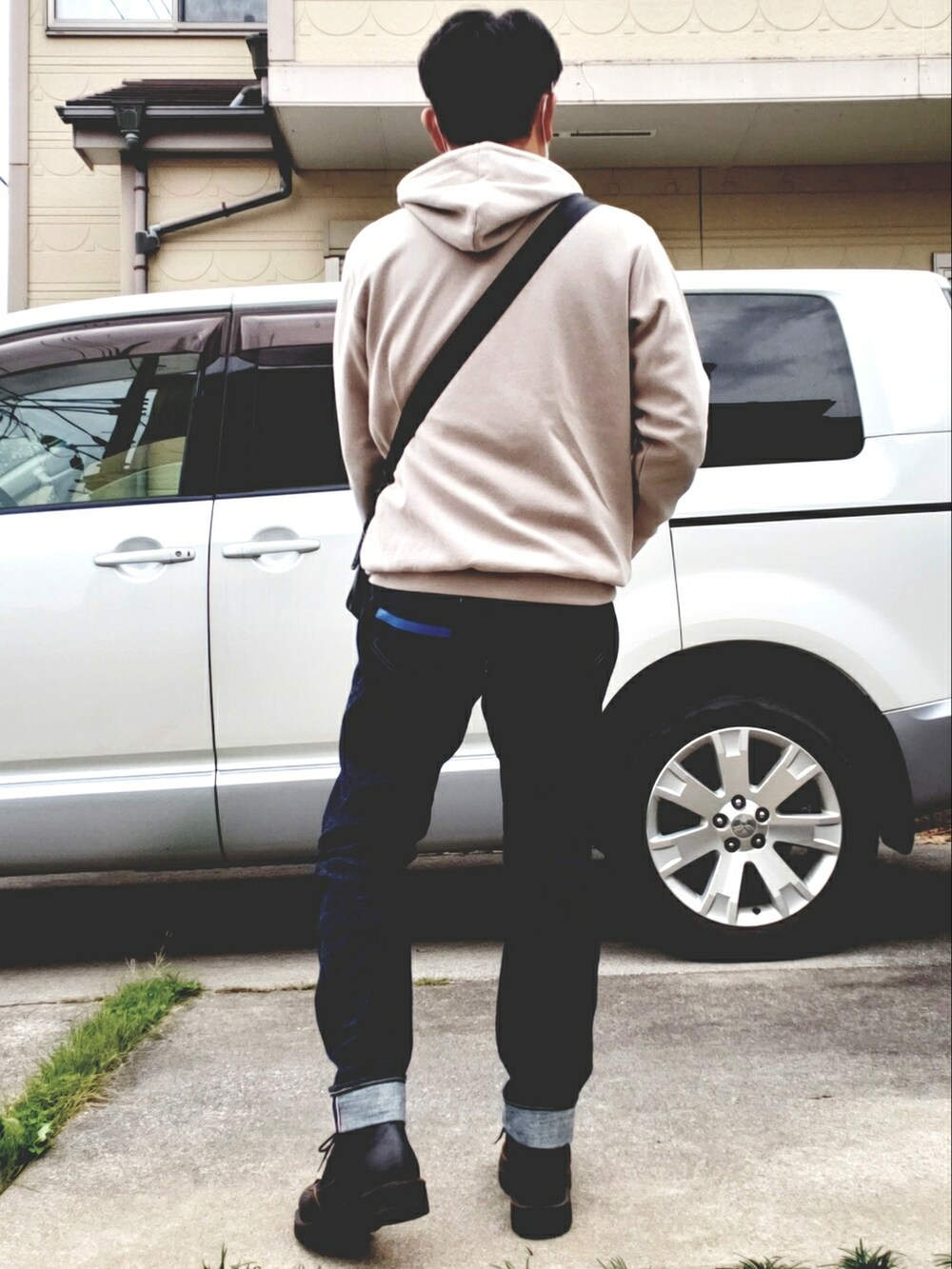 ブルー系のデニムパンツ、ブラック系のブーツ、ブラック系のショルダーバッグを着用したメンズの秋コーディネートの2枚目の写真