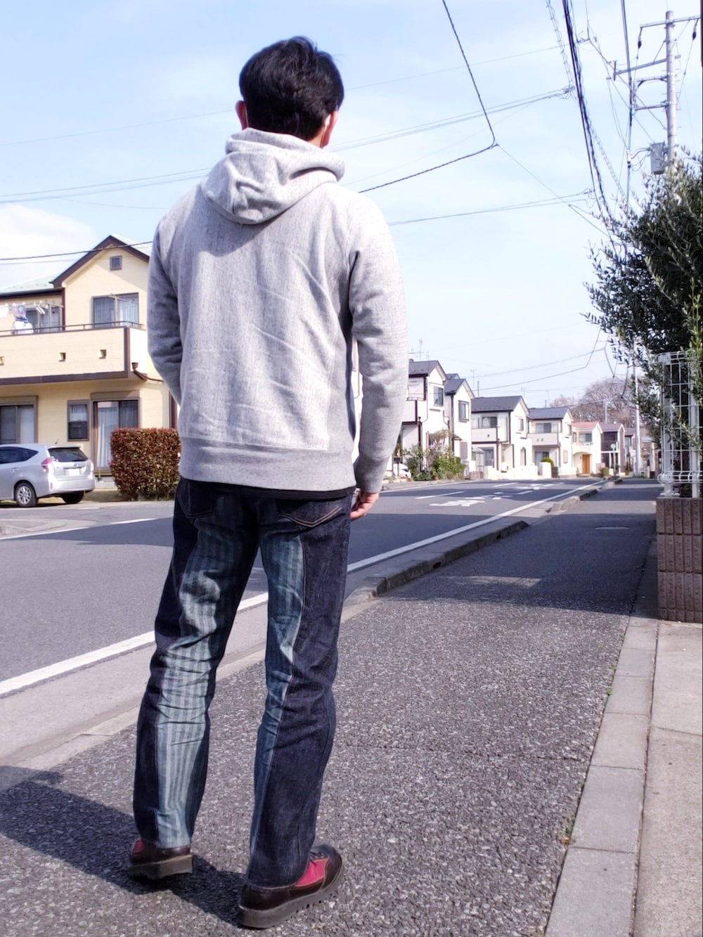 レッド系のシューズ、その他のデニムパンツ、グレー系のパーカーを着用したメンズの春コーディネートの2枚目の写真