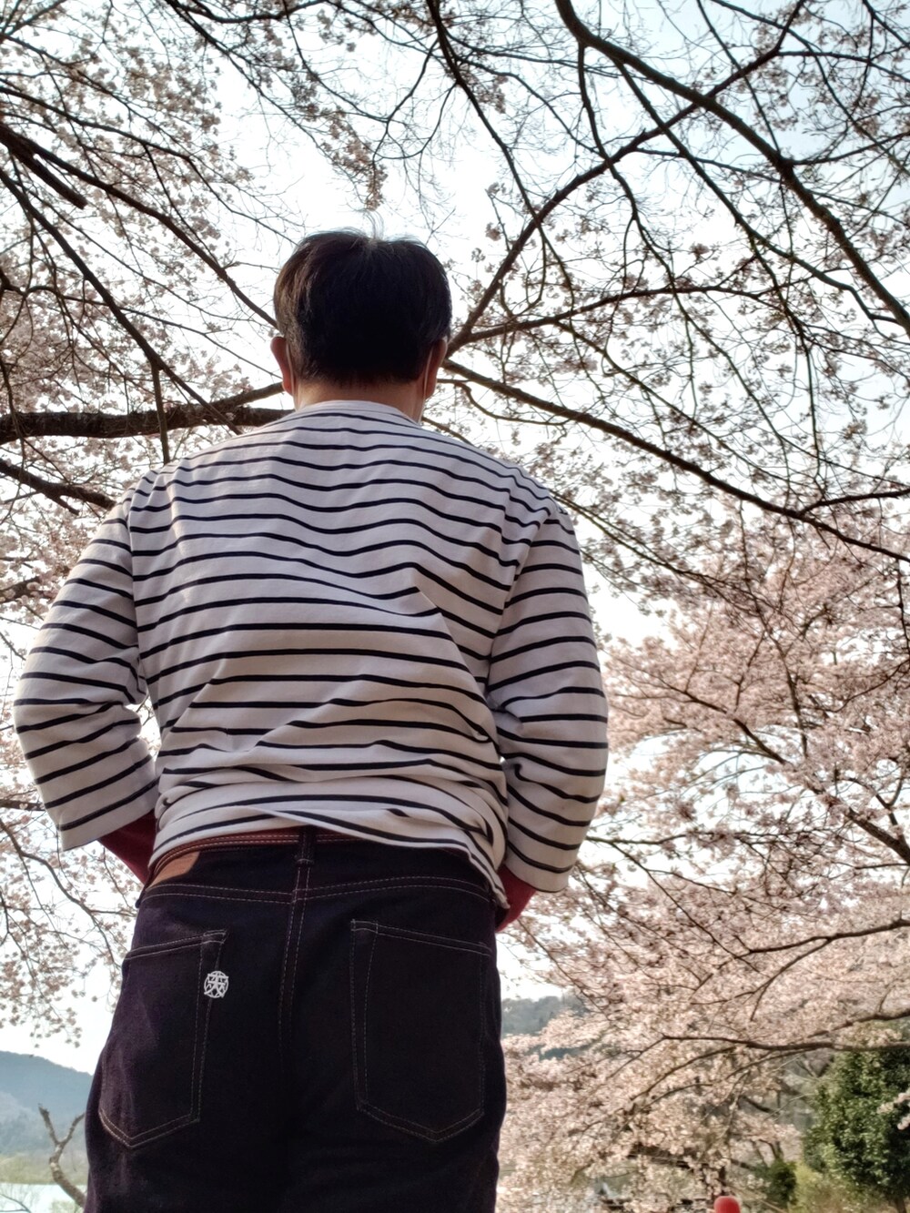 レッド系のデニムパンツ、グリーン系のブルゾン、ブラック系のショルダーバッグを着用したメンズの春コーディネートの3枚目の写真