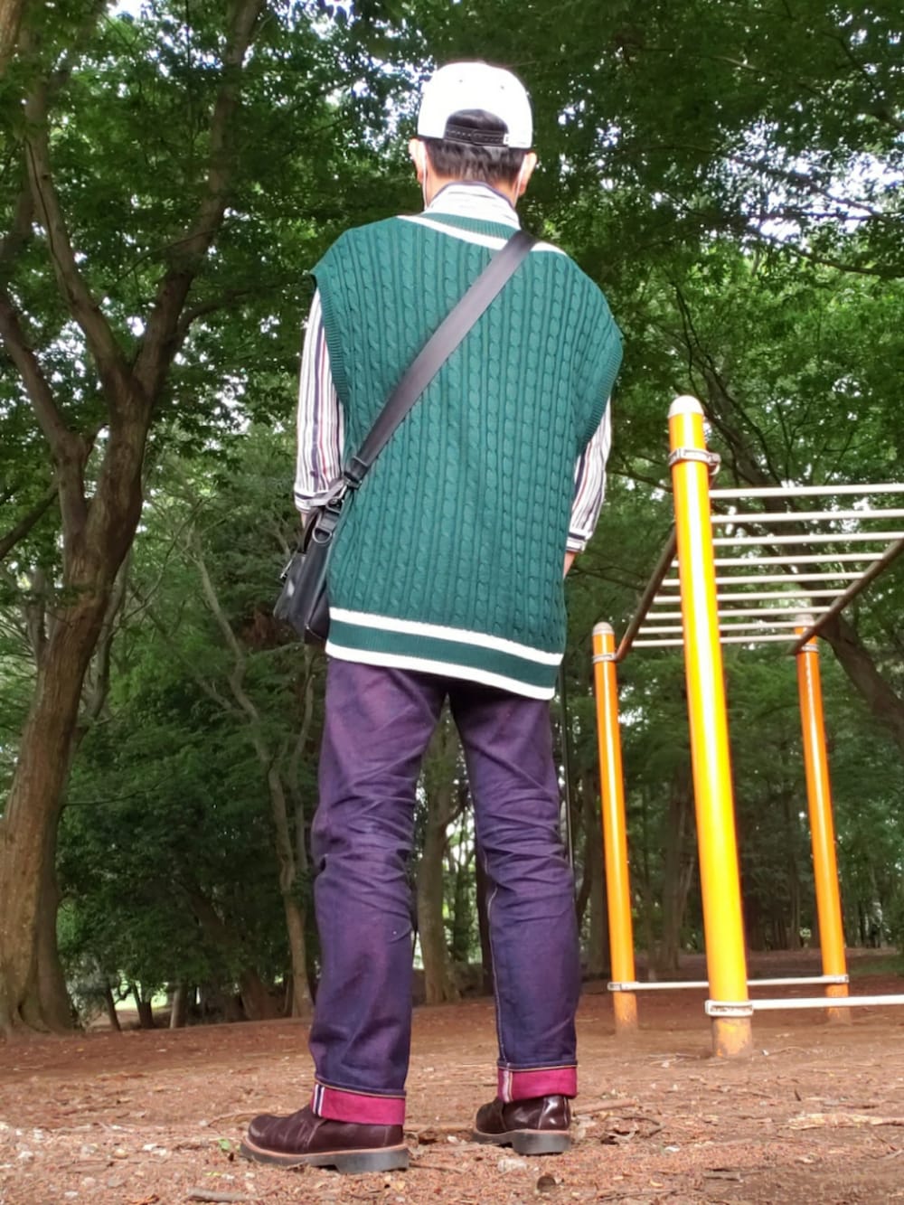 グリーン系のベスト、ホワイト系のシャツ/ブラウス、レッド系のデニムパンツを着用したメンズの春コーディネートの2枚目の写真