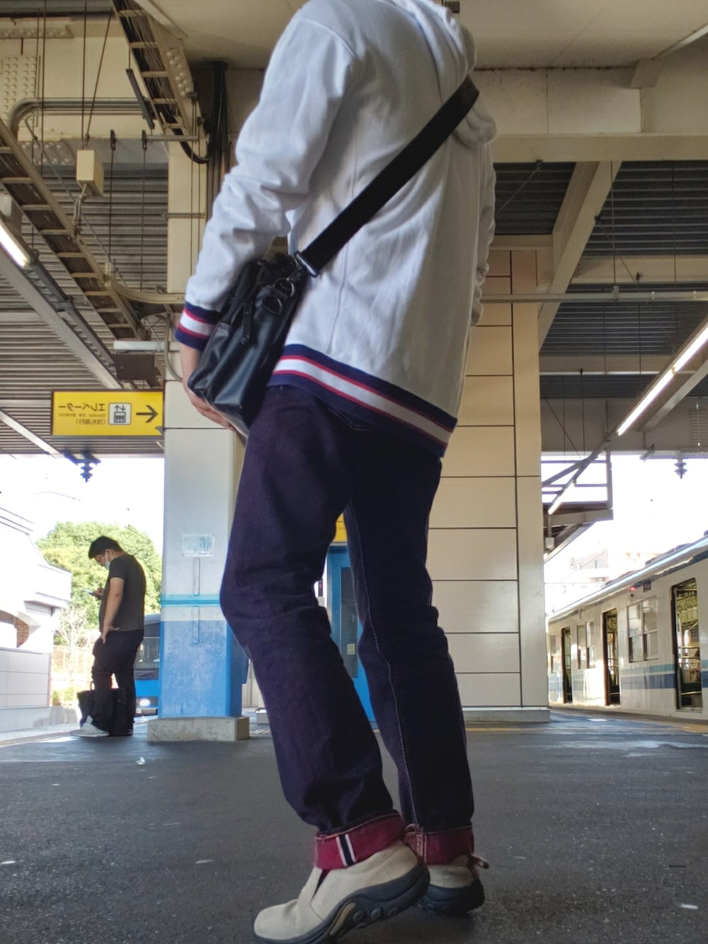 ベージュ系のスニーカー、レッド系のデニムパンツ、ブラック系のバッグを着用したメンズの秋コーディネートの2枚目の写真