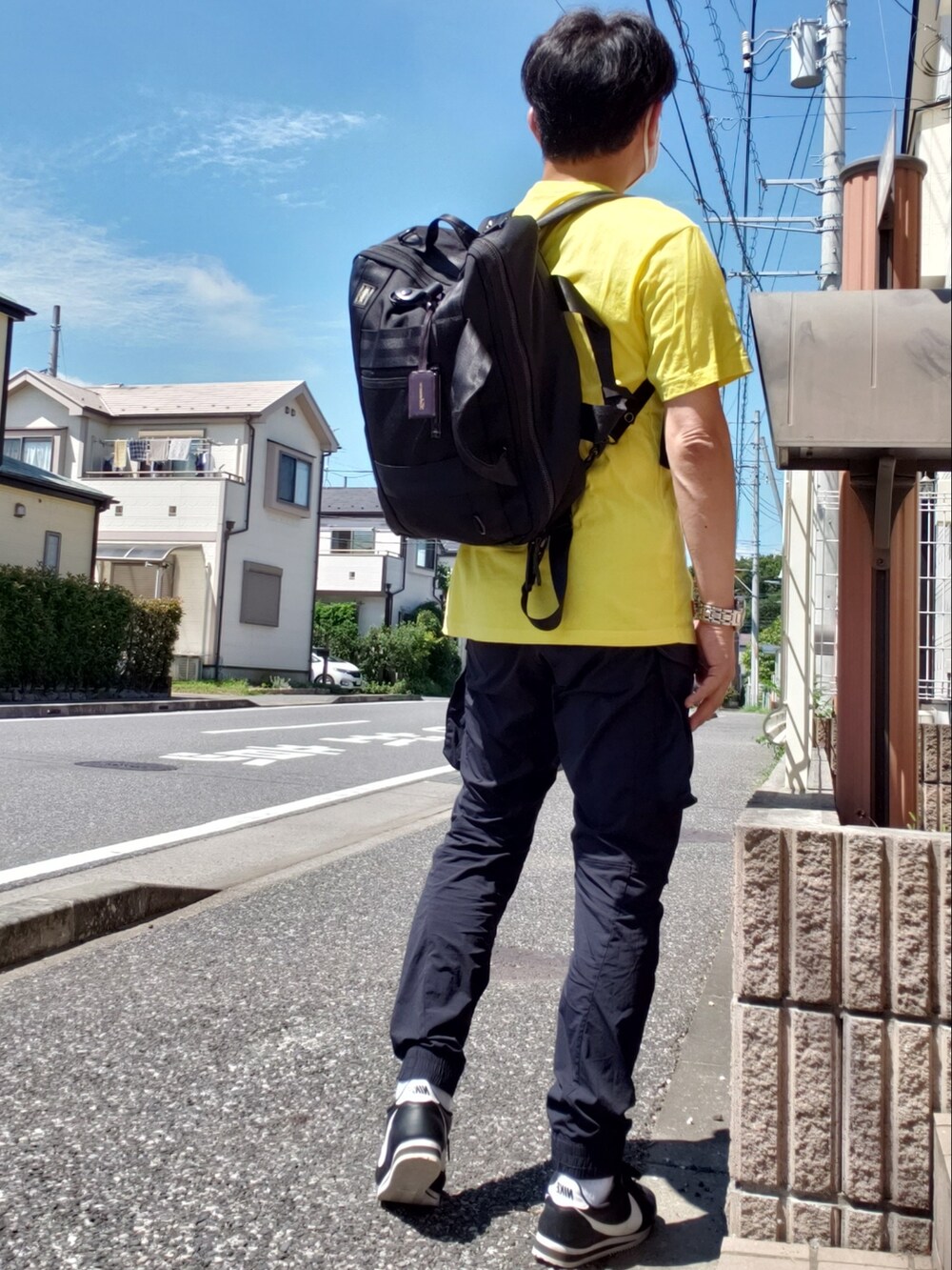 イエロー系のTシャツ/カットソー、ブラック系のカーゴパンツ、ブラック系のスニーカーを着用したメンズの夏コーディネートの2枚目の写真