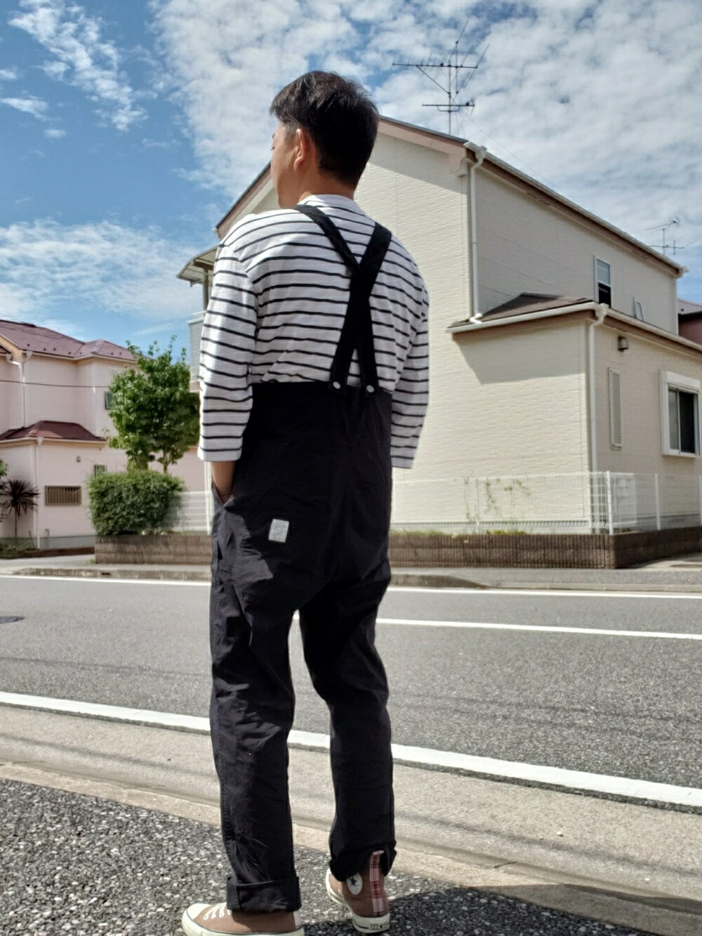 ブラック系のサロペット/オーバーオール、ブラウン系のスニーカー、ホワイト系のTシャツ/カットソーを着用したメンズの秋コーディネートの2枚目の写真