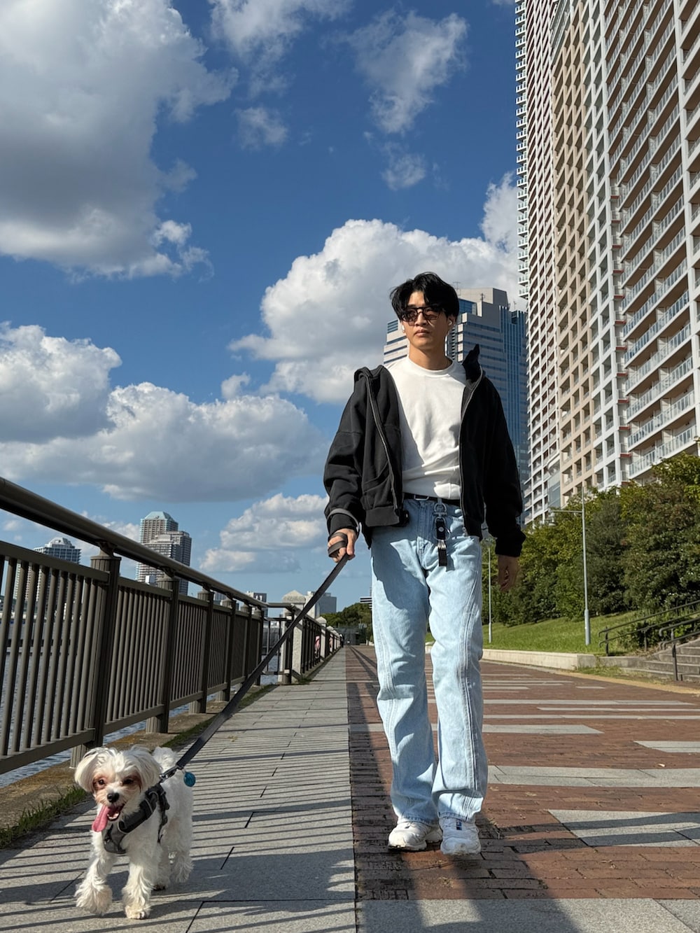 ブルー系のデニムパンツ、ホワイト系のスニーカー、グレー系のパーカーを着用したメンズの秋コーディネートの4枚目の写真