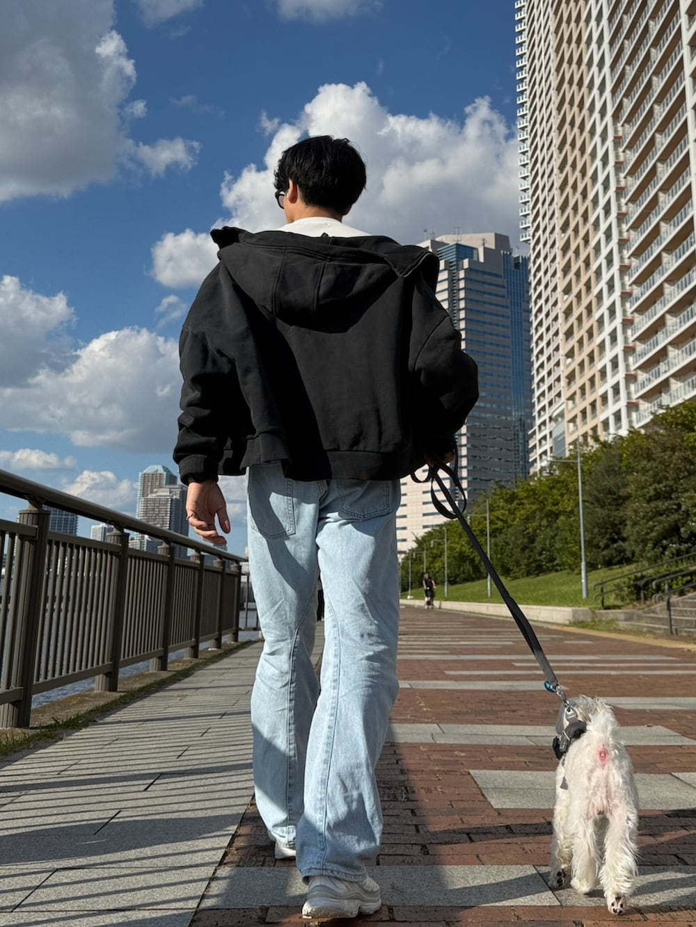 ブルー系のデニムパンツ、ホワイト系のスニーカー、グレー系のパーカーを着用したメンズの秋コーディネートの2枚目の写真