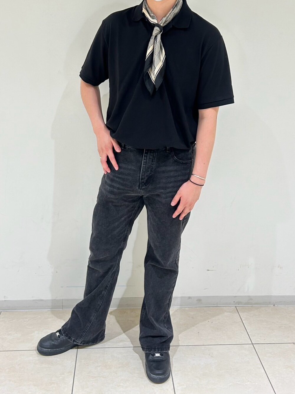 ブラック系のポロシャツ、ブラック系のデニムパンツ、ブラック系のスニーカーを着用したメンズの夏コーディネートの2枚目の写真