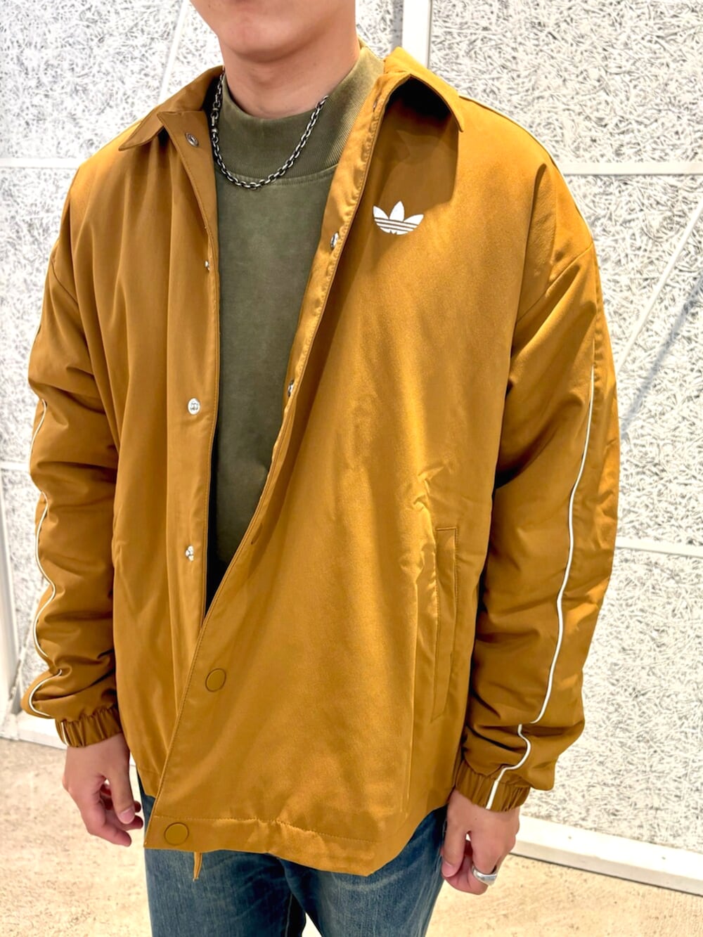 ブラウン系のブルゾン、グリーン系のトップス、ブラウン系のスニーカーを着用したメンズの秋コーディネートの3枚目の写真