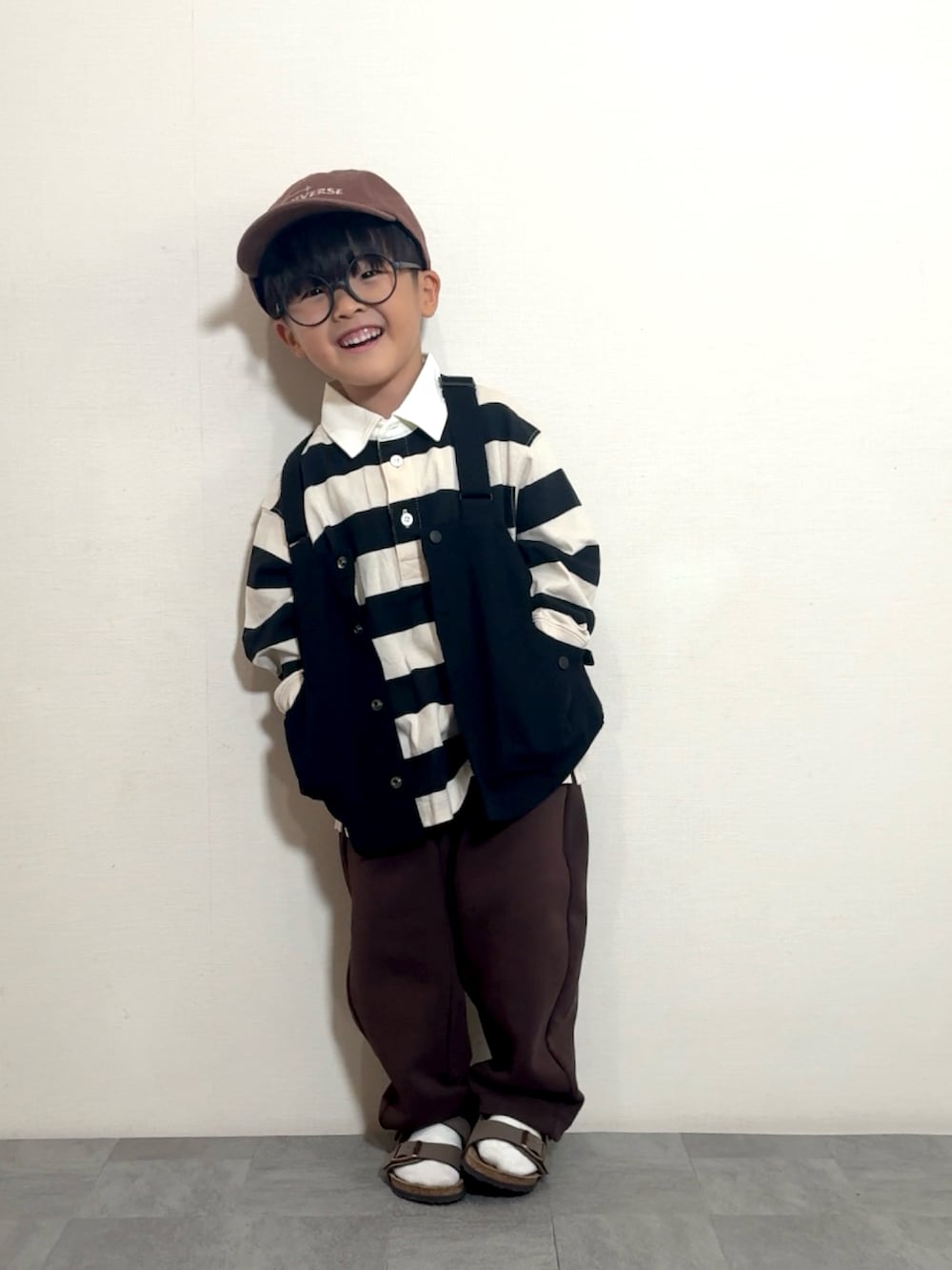 ブラウン系のサンダル、ブラック系のベスト、ホワイト系のポロシャツを着用したキッズの夏コーディネートの2枚目の写真